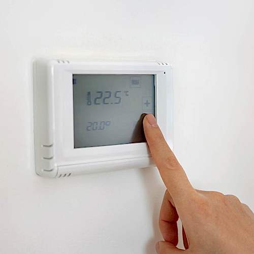 lowering-the-temperature-for-energy-saving-human-hand-adjusting-digital-central-heating-thermostat-at-home-Broughton Astley